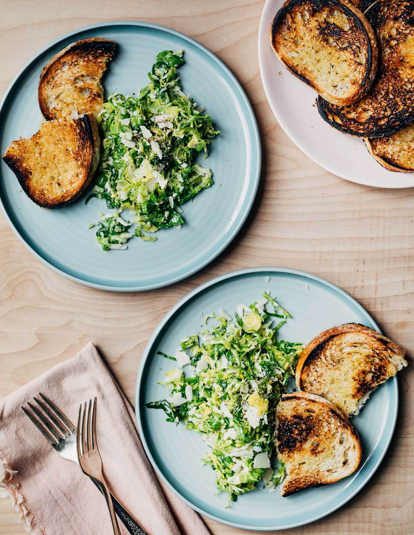 Two plates with a Brussels sprout salad and croutons. 