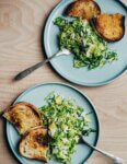 Two plates with a Brussels sprout salad and croutons.