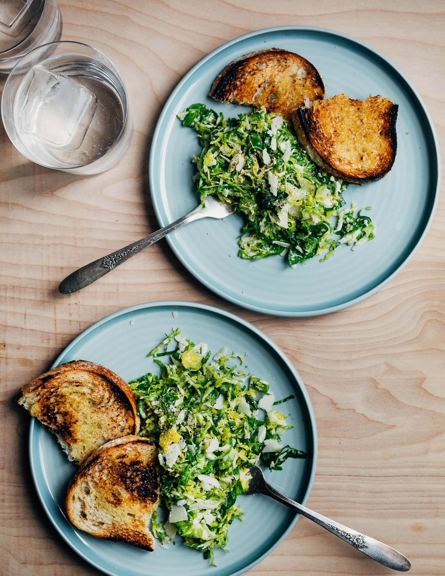 Two plates with a Brussels sprout salad and croutons. 