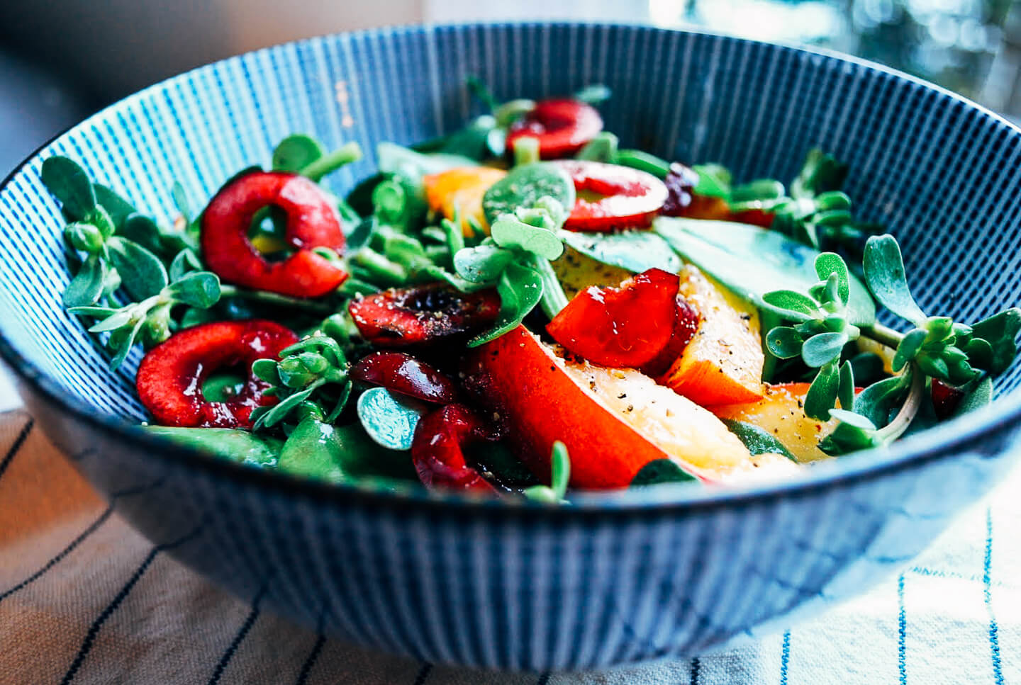 A vibrant purslane salad dotted with sweet cherries and ripe peaches. 