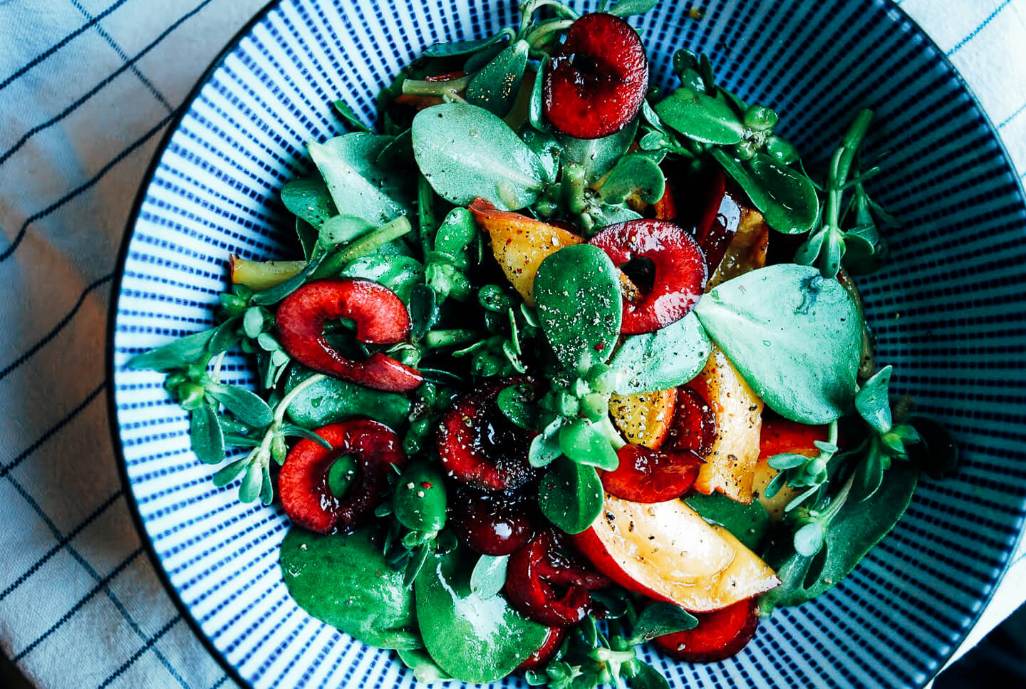A vibrant purslane salad dotted with sweet cherries and ripe peaches. 