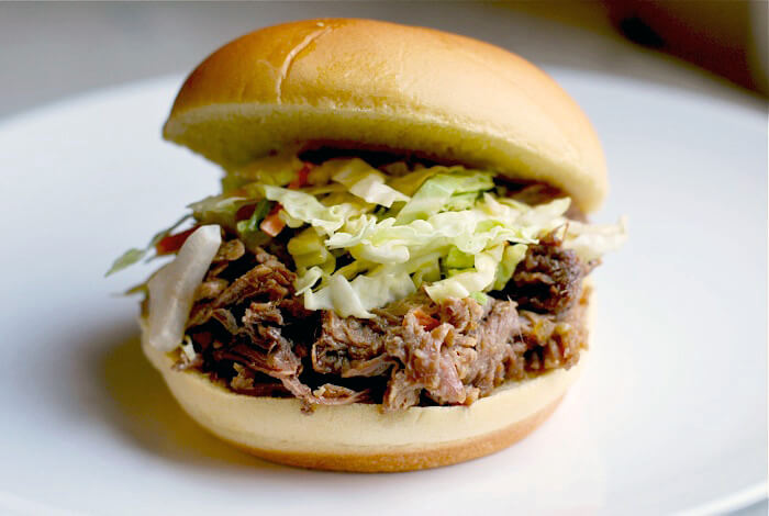 A pulled pork sandwich with green slaw. 