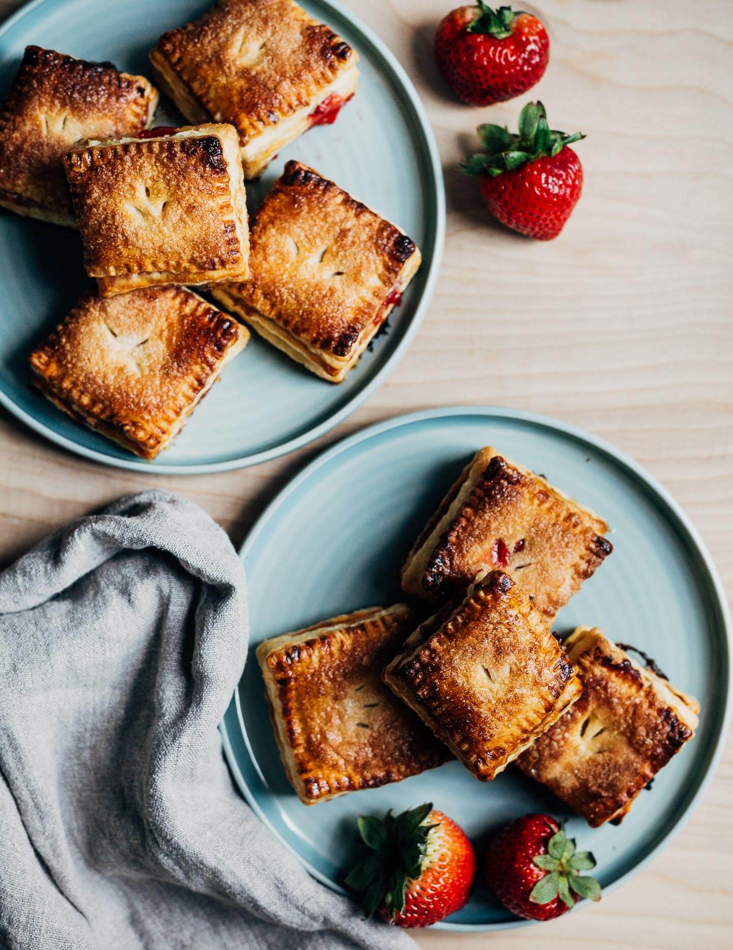 Two plates piled with little strawberry basil hand pies. 