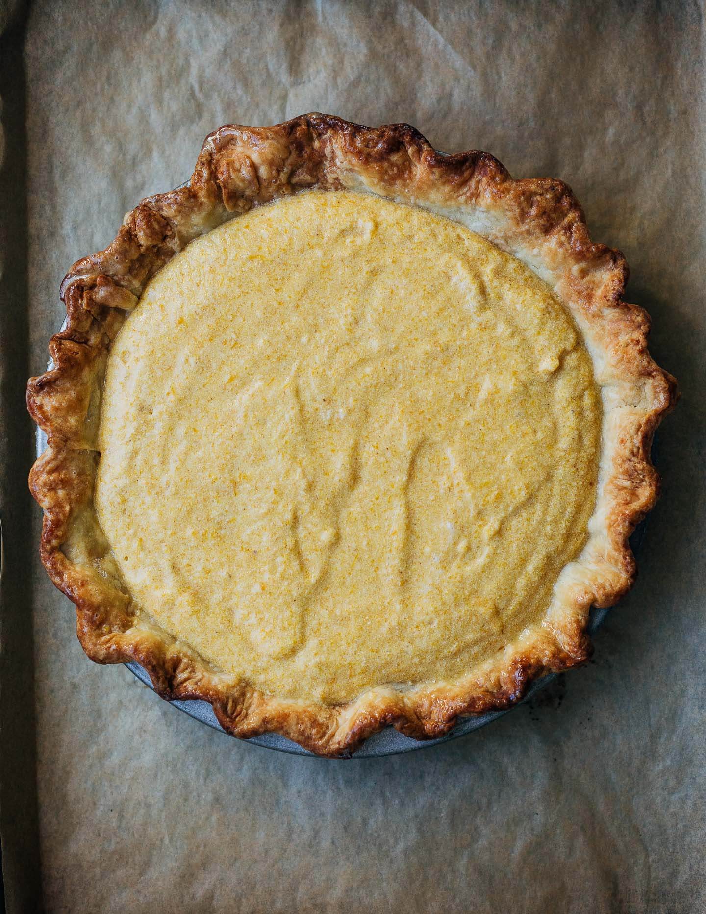 An unbaked pumpkin pie on a baking sheet. 