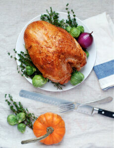 A roast turkey breast with carving tools on a table.