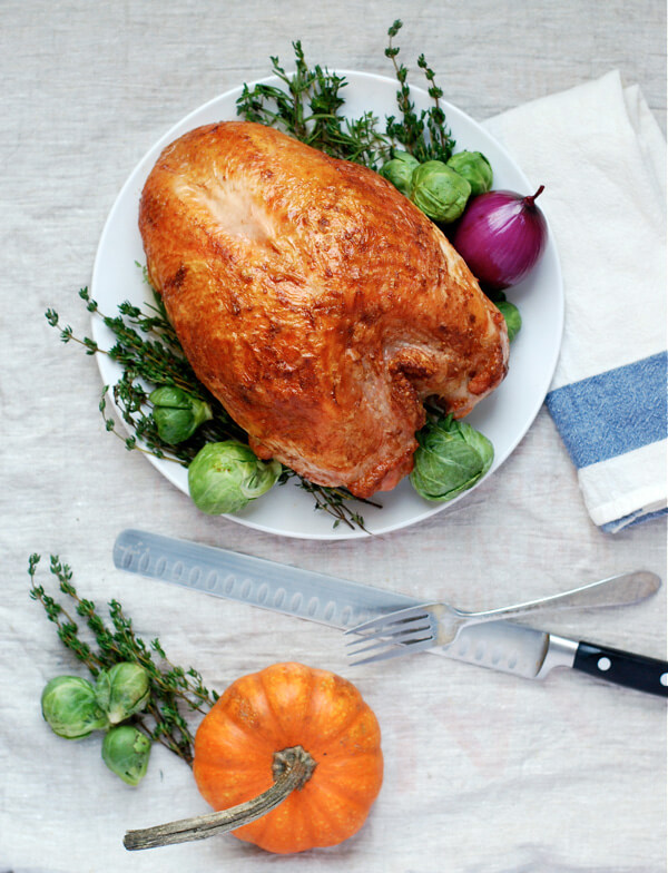 A roast turkey breast with carving tools on a table. 
