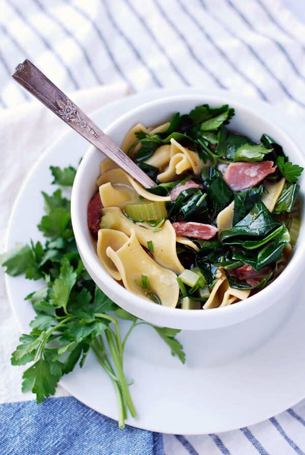 A bowl of ham hock and collard soup garnished with parsley. 