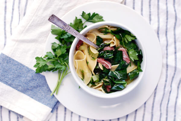 A bowl of ham hock and collard soup garnished with parsley. 