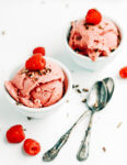 Two small bowls with raspberry frozen yogurt with a raspberry on top.