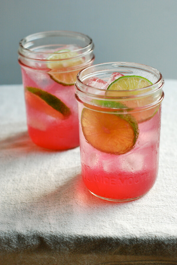 Two glasses with lime slices and concord syrup. 