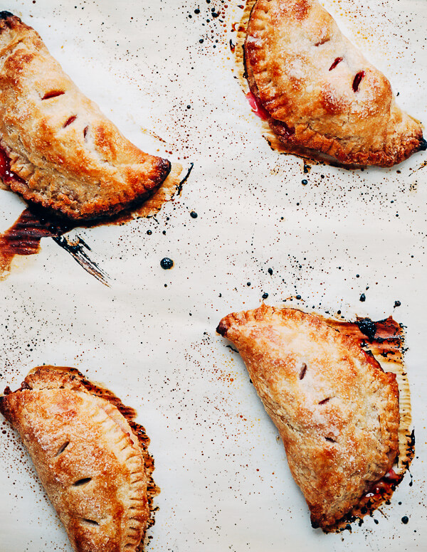 Freshly baked sour cherry hand pies on a baking sheet. 