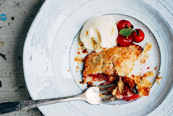 A dish with a sour cherry hand pie and ice cream. There’s a fork and a bite has been taken out of the pie. 