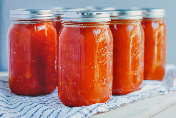 A tabletop with several jars of canned crushed tomatoes. 