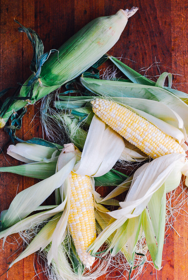 Partially shucked ears of corn on a table. 