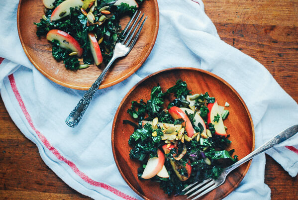 Two plates of kale salad with forks and a napkin. 