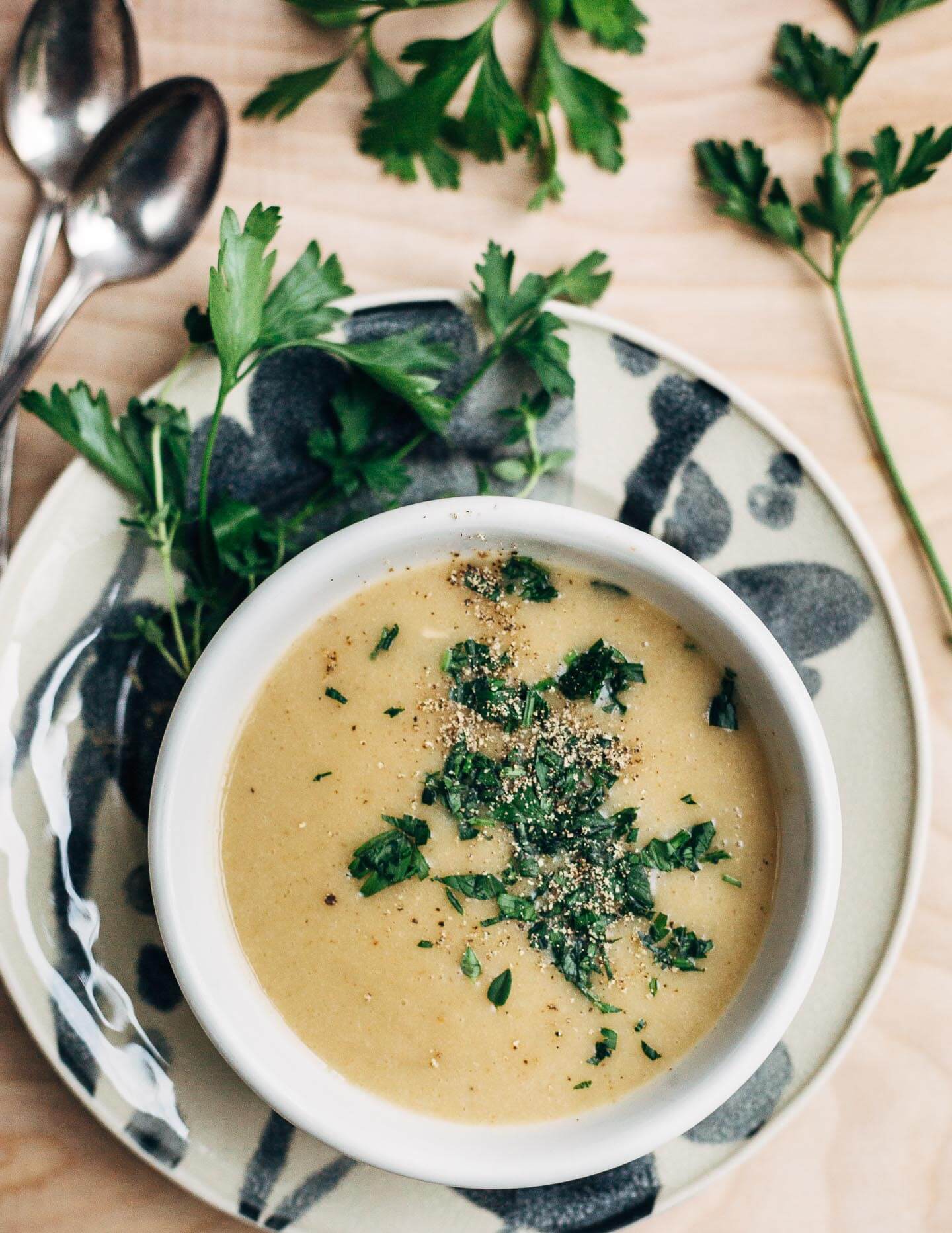 A bowl of garlic soup topped with minced herbs and lots of fresh ground pepper. 