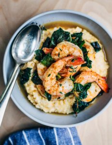 A bowl with grits, green, and spice-dusted shrimp.