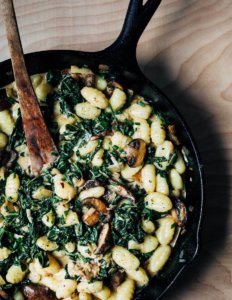 A cast iron skillet with collards and mushrooms