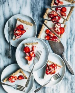 A strawberry tart sliced up, and several plates with tart slices.