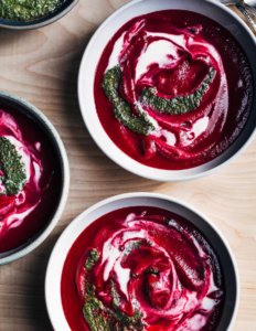 Bowls of beet soup with a cream swirl in the middle.