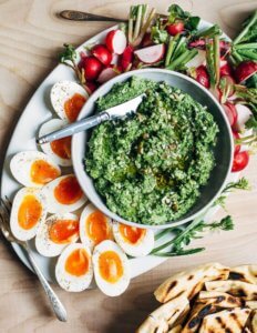A platter with pesto, halved eggs and radishes.