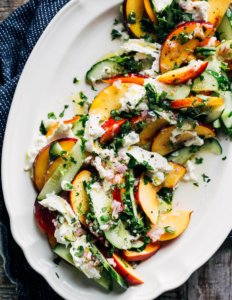 A large platter with a cucumber and nectarine salad.