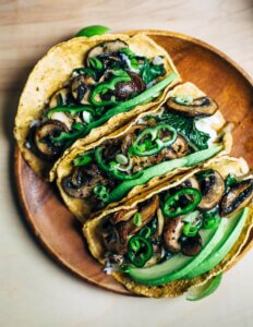 Three mushroom tacos topped with sliced chilies.