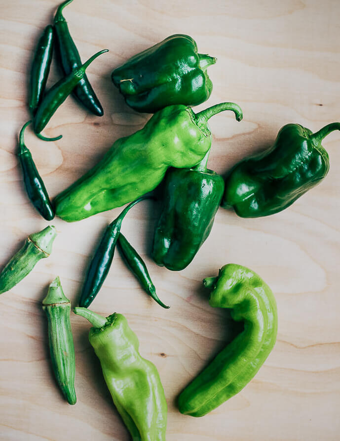 Green peppers and chilies on a tabletop. 