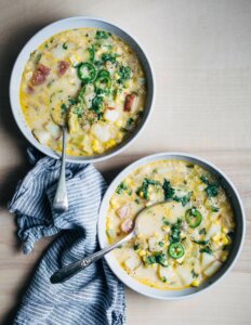 Two bowls of coconut milk corn chowder with sliced jalapenos on top.