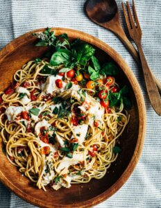 A bowl with pasta, roasted cherry tomatoes, and mozzarella.