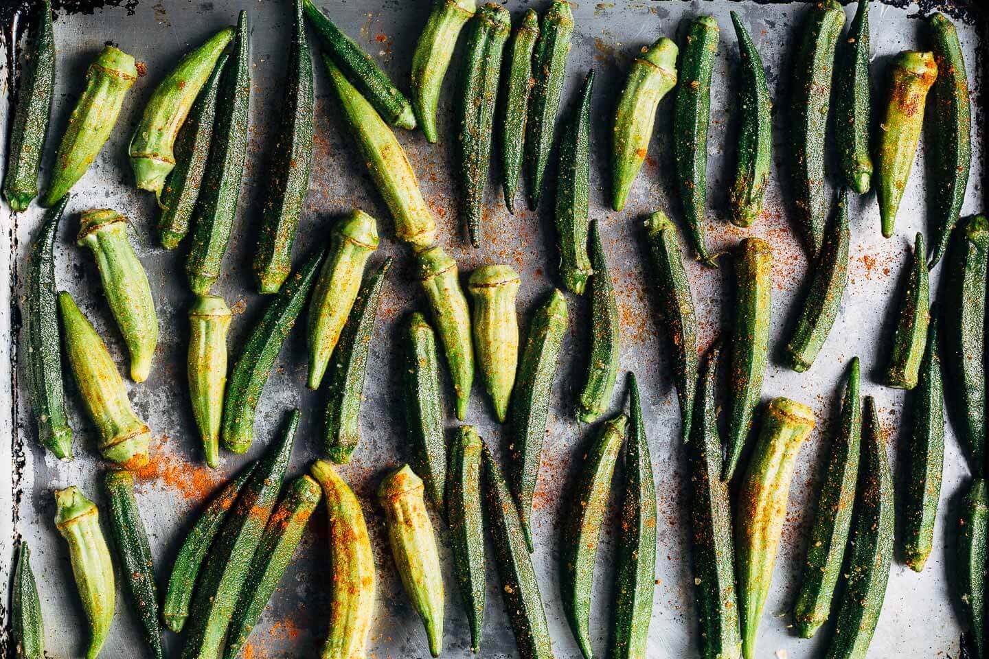 Halved okra arranged on a baking sheet. 