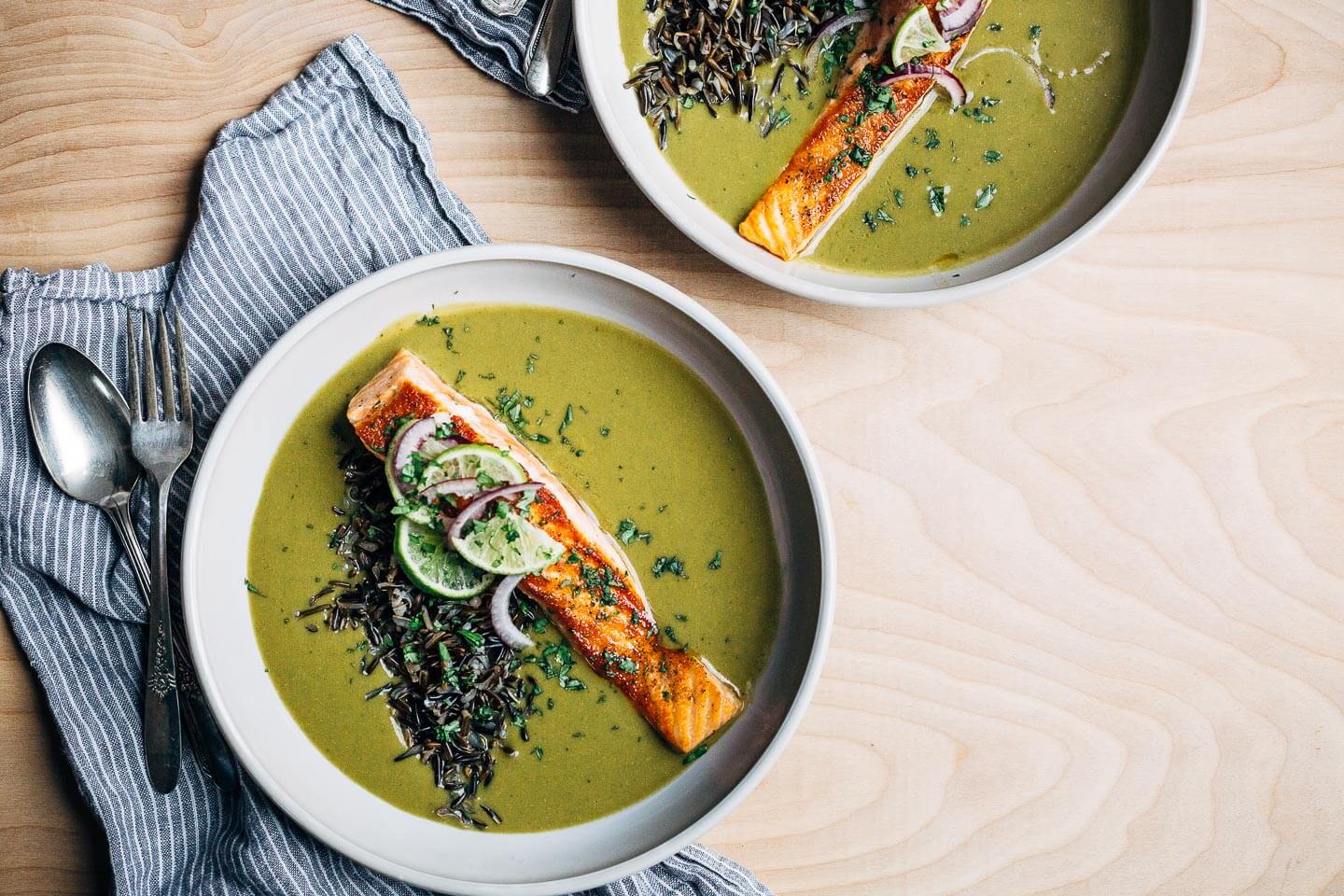 Nourishing green soup with creamy coconut milk and wild rice topped with a pan-seared salmon fillet.