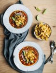Hearty pinto bean chili with a flavorful tomato base flecked with leeks, chili peppers, and hominy and topped with fresh cilantro, lime, sliced avocado and radish, and crunchy corn chips.