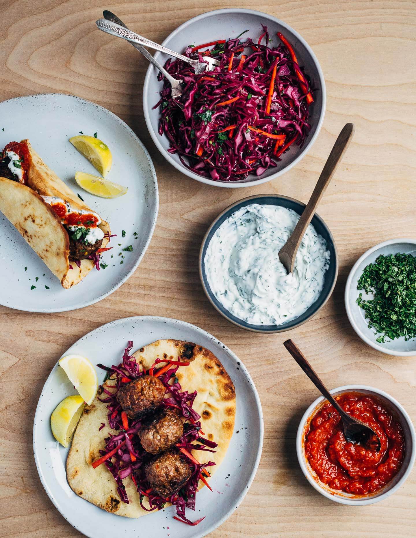 Exceptionally delicious merguez meatball flatbreads layered with red cabbage slaw, herbed yogurt, and harissa. 