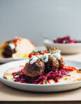 Exceptionally delicious merguez meatball flatbreads layered with red cabbage slaw, herbed yogurt, and harissa.