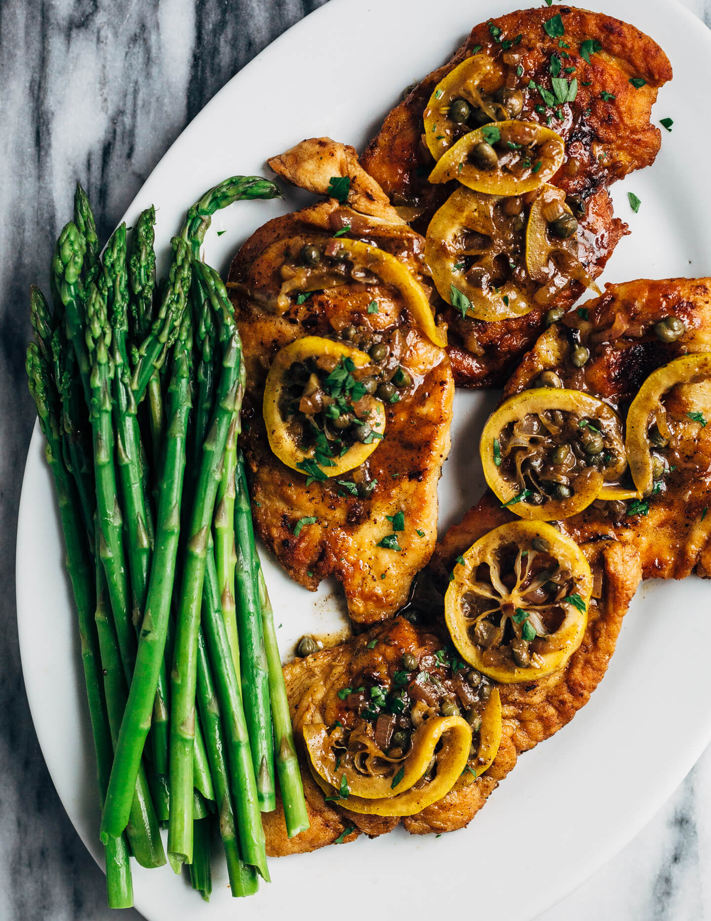 Weeknight-perfect chicken piccata topped with a bright and buttery caper sauce and served alongside angel hair pasta and asparagus.