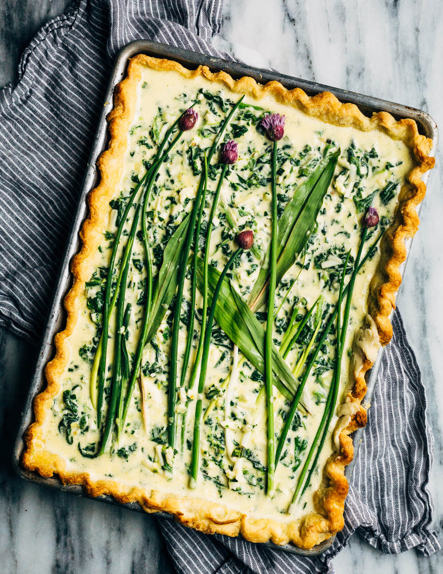 Ideal for Mother's Day brunch or spring gatherings, this sheet pan spinach quiche, made with ramps, green garlic, and chives, is a delicious way to feed a crowd. 