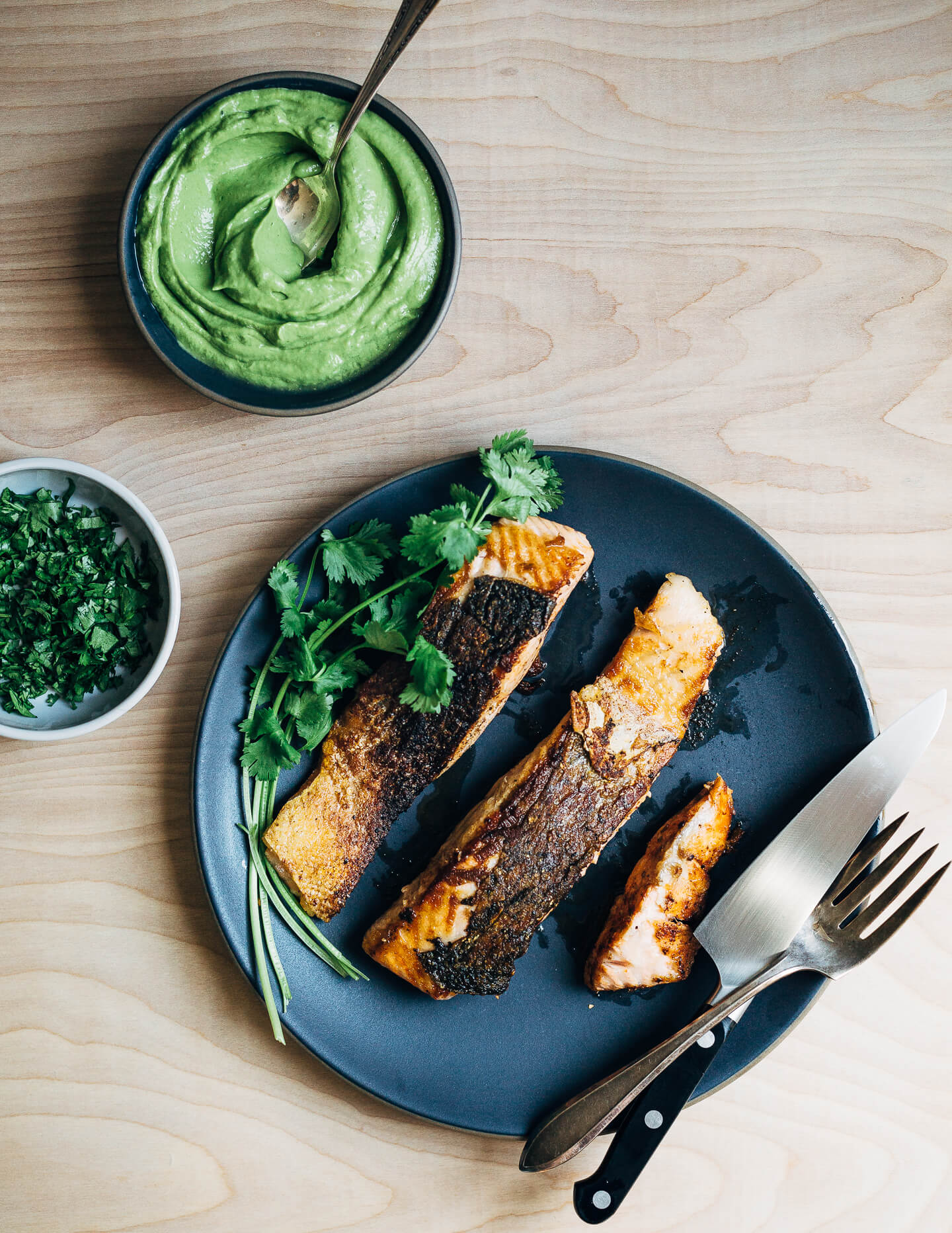 Spicy salmon tacos make for a delicious springtime feast. Tender, crisp skinned salmon is suffused with chipotle chili powder, cumin, and coriander, tucked into toothsome corn tortillas, and layered with a fennel and red cabbage slaw and an easy cilantro-avocado blender sauce. 