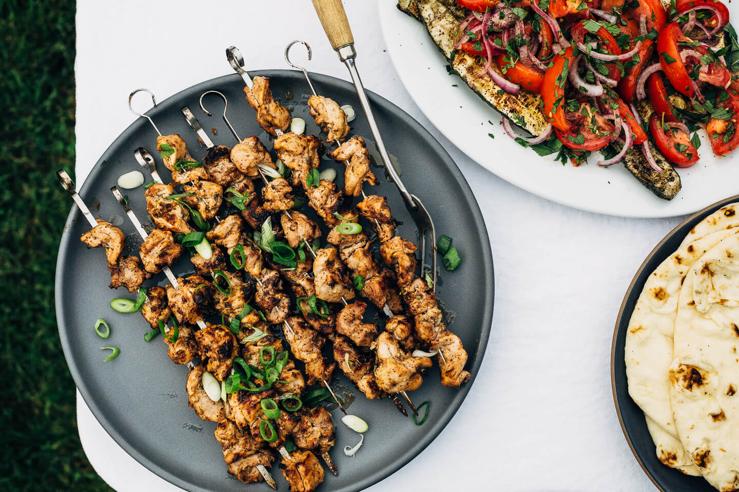 Deliciously tender lemon- and yogurt-marinated grilled chicken kebobs make for a vibrant summer cookout. The grilled chicken skewers are served alongside grilled flatbreads, tzatziki, and an herbed salad made with grilled zucchini, tomato, and red onion.