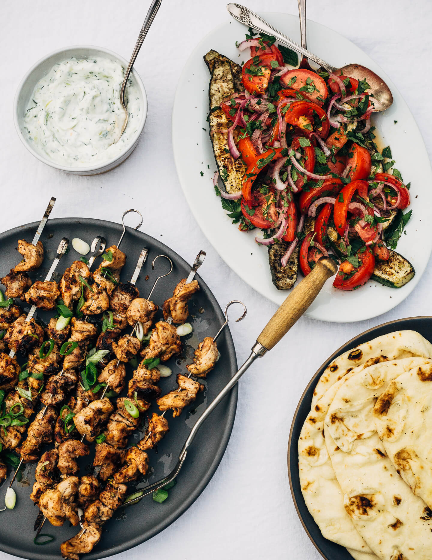 Deliciously tender lemon- and yogurt-marinated grilled chicken kebobs make for a vibrant summer cookout. The grilled chicken skewers are served alongside grilled flatbreads, tzatziki, and an herbed salad made with grilled zucchini, tomato, and red onion.