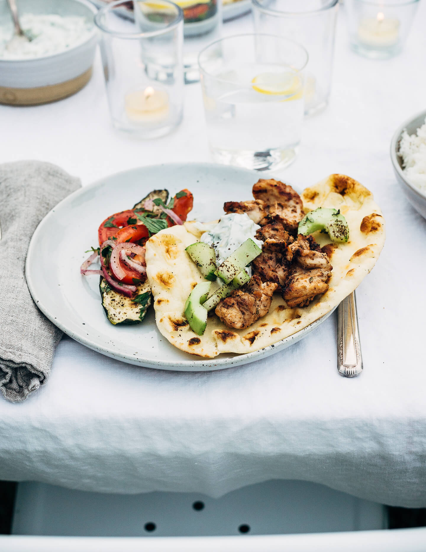 Deliciously tender lemon- and yogurt-marinated grilled chicken kebobs make for a vibrant summer cookout. The grilled chicken skewers are served alongside grilled flatbreads, tzatziki, and an herbed salad made with grilled zucchini, tomato, and red onion.