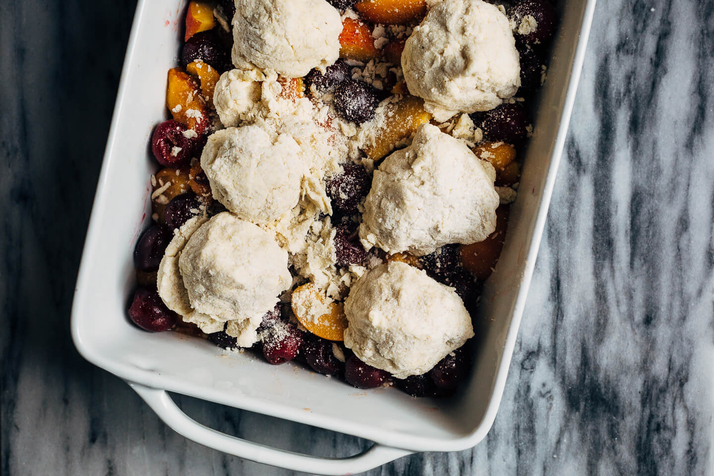 A summery cherry and peach cornmeal cobbler that pairs the sweetness of ripe summer stone fruits with a tender, faintly sweet, cornmeal biscuit topping. 