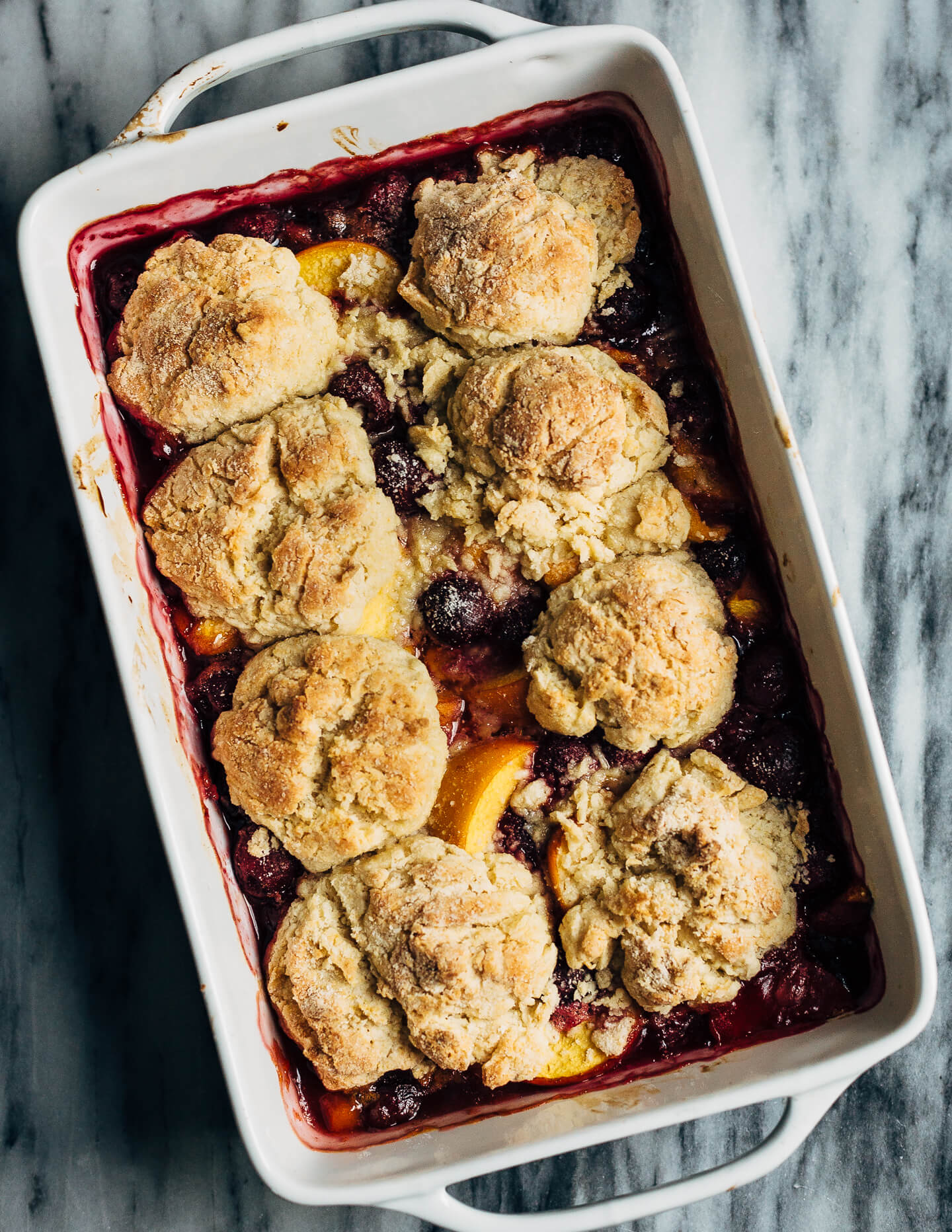 A summery cherry and peach cornmeal cobbler that pairs the sweetness of ripe summer stone fruits with a tender, faintly sweet, cornmeal biscuit topping. 