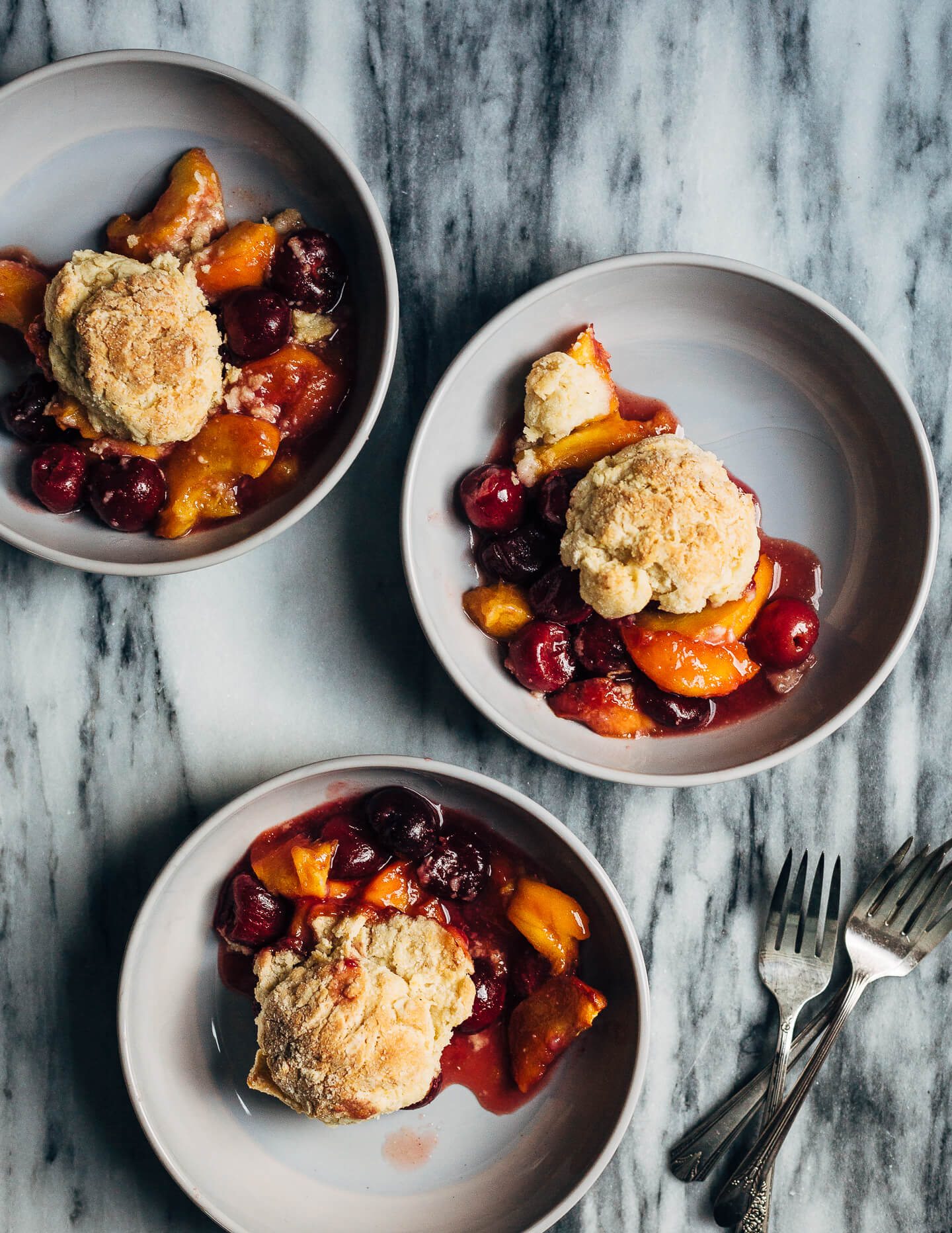 A summery cherry and peach cornmeal cobbler that pairs the sweetness of ripe summer stone fruits with a tender, faintly sweet, cornmeal biscuit topping. 