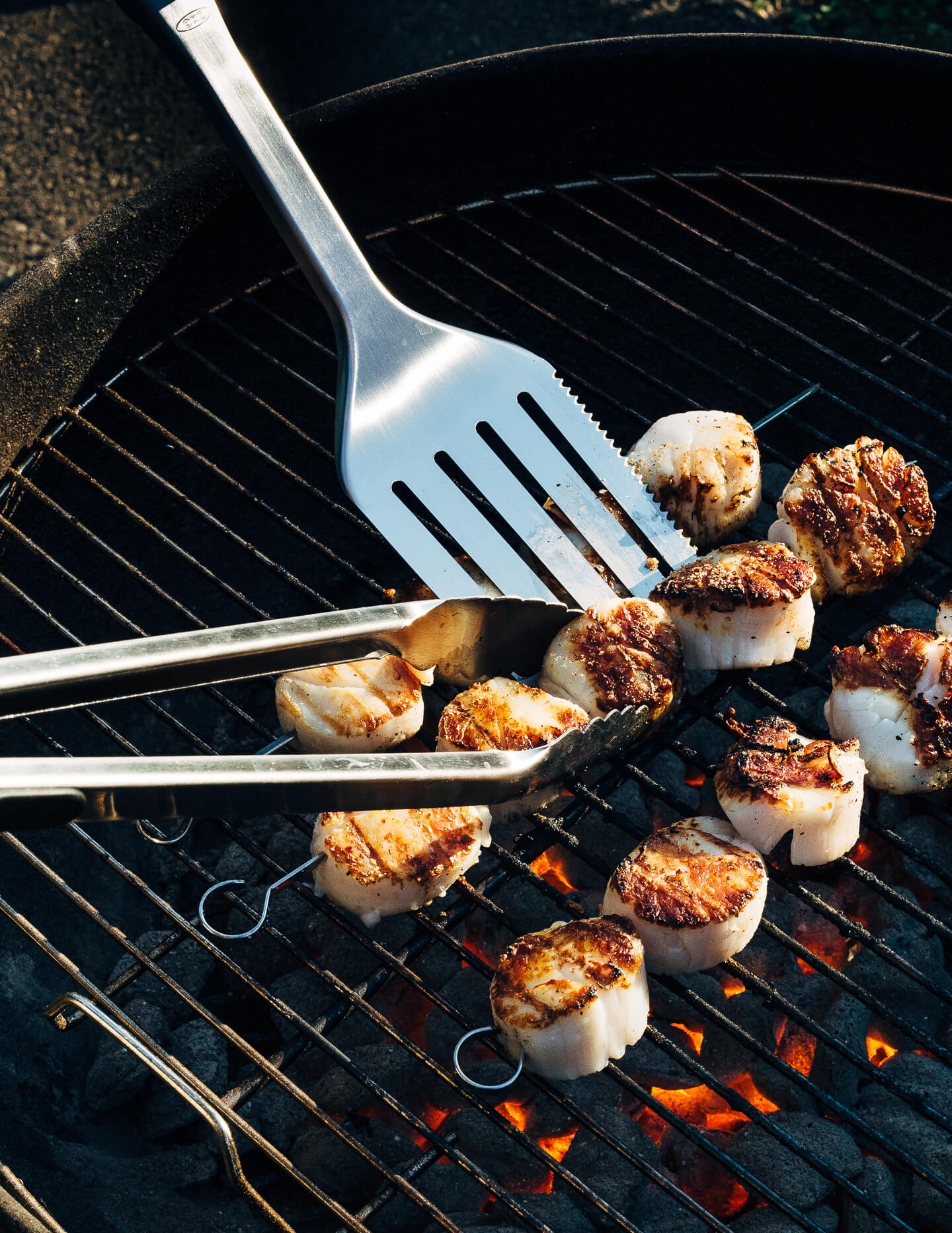 A simple grilled summer feast featuring grilled scallops served atop zucchini noodles tossed with charred corn and fresh herbs.