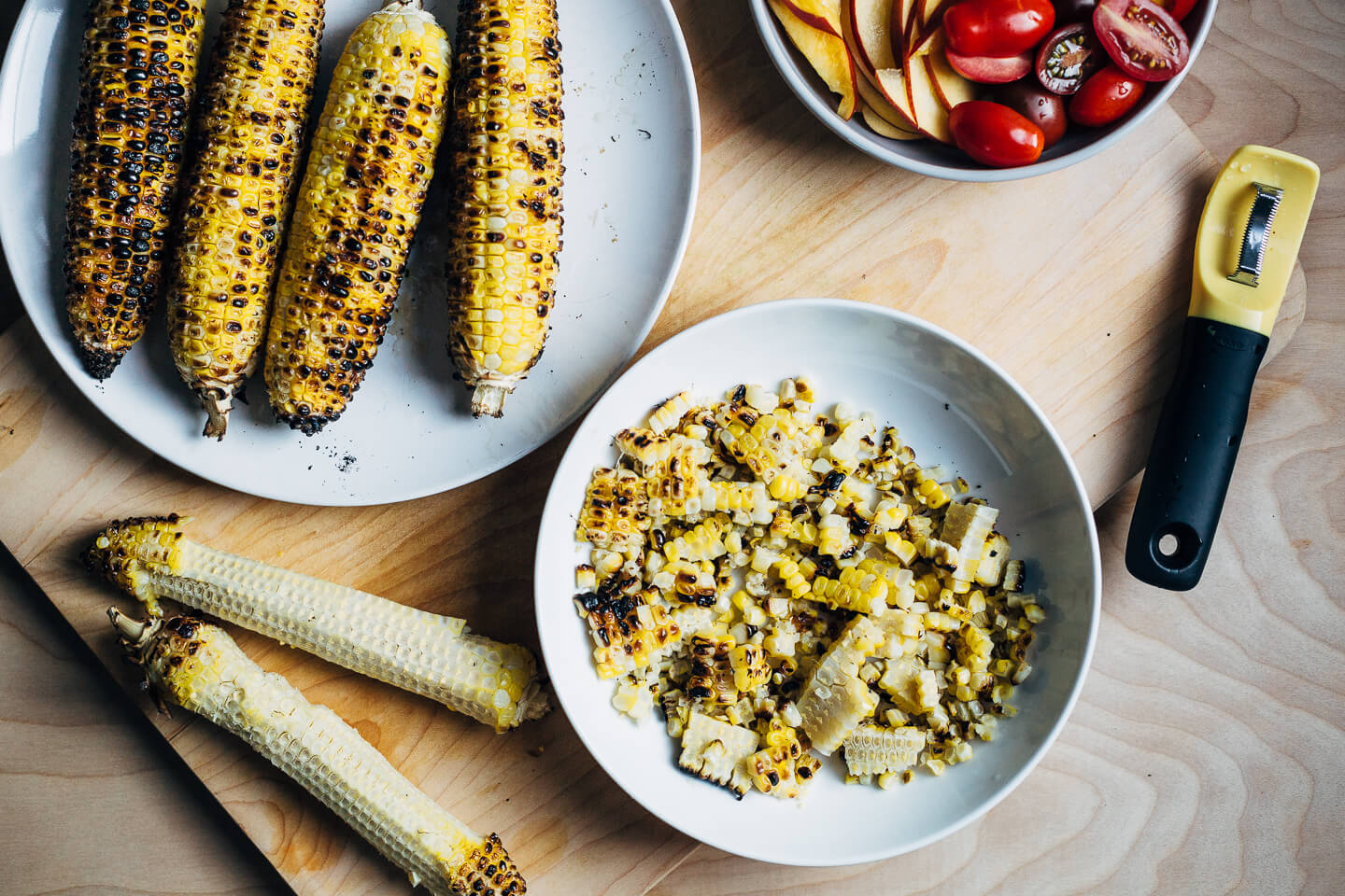 A simple grilled summer feast featuring grilled scallops served atop zucchini noodles tossed with charred corn and fresh herbs.