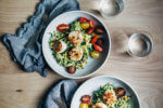 A simple grilled summer feast featuring grilled scallops served atop zucchini noodles tossed with charred corn and fresh herbs.