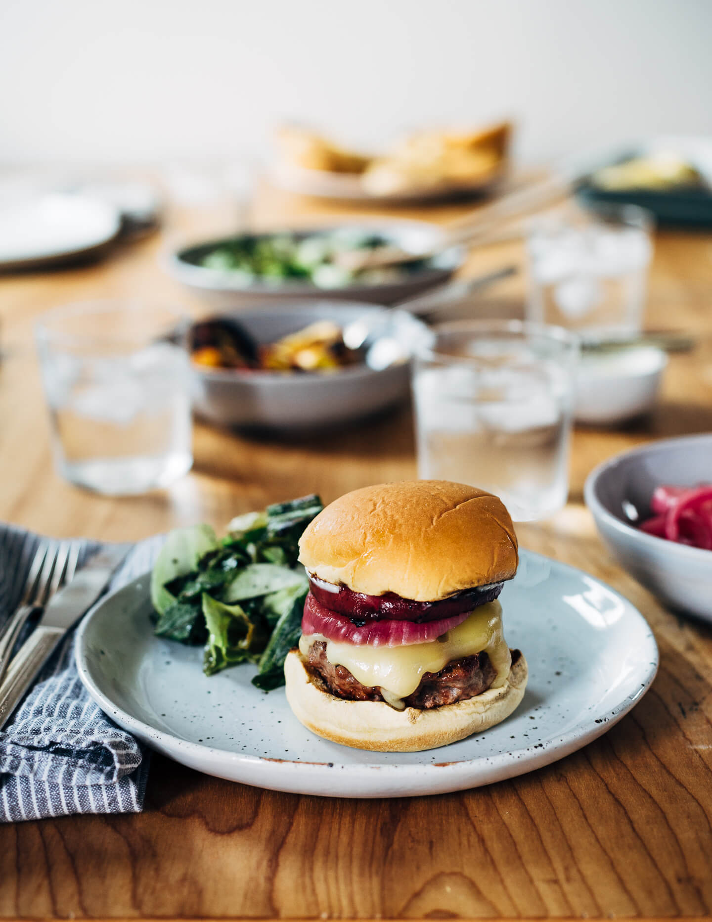 Juicy pork burgers perfectly grilled and topped with velvety melted Raclette cheese, grilled nectarine slices, crisp pickled red onions, and a smear of mayo.