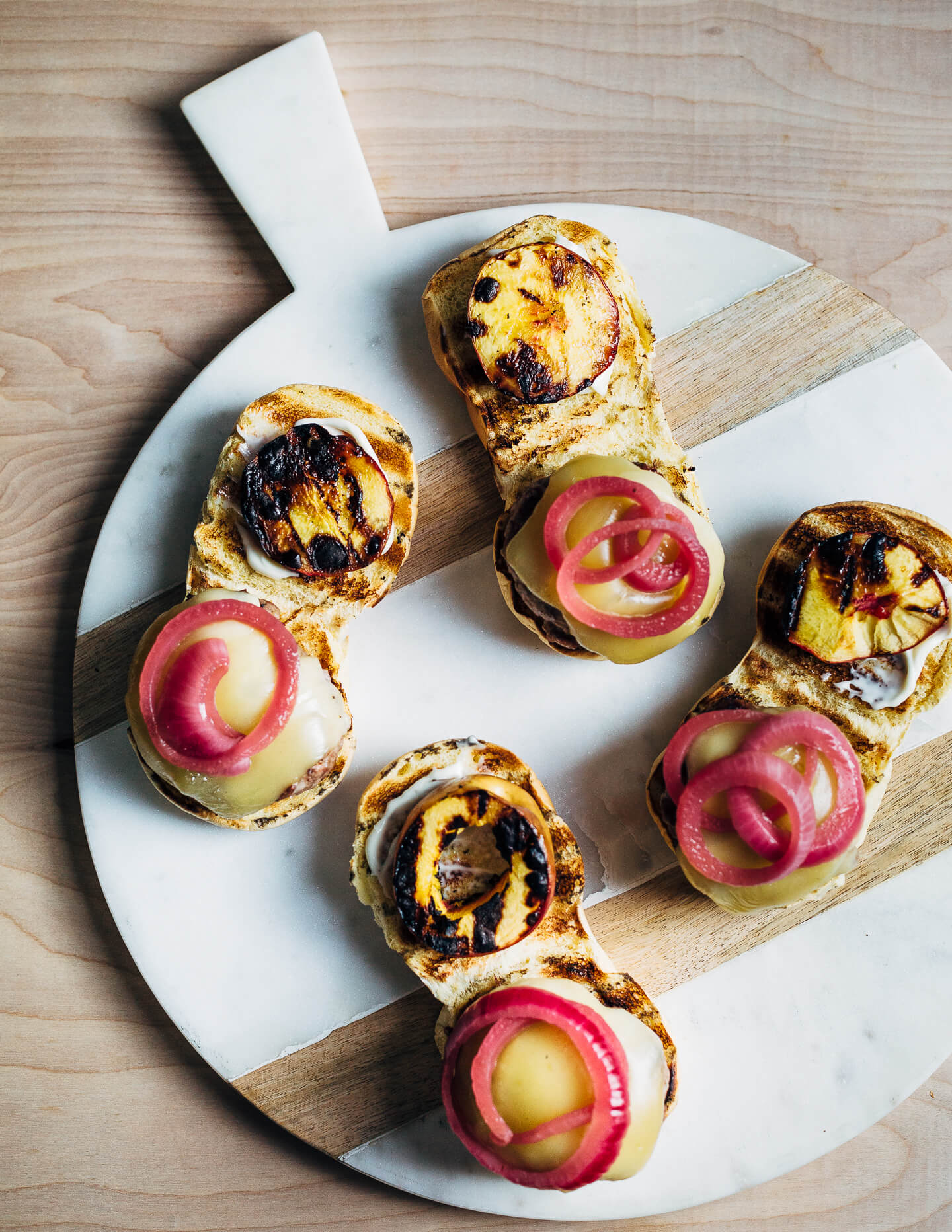 Juicy pork burgers perfectly grilled and topped with velvety melted Raclette cheese, grilled nectarine slices, crisp pickled red onions, and a smear of mayo.