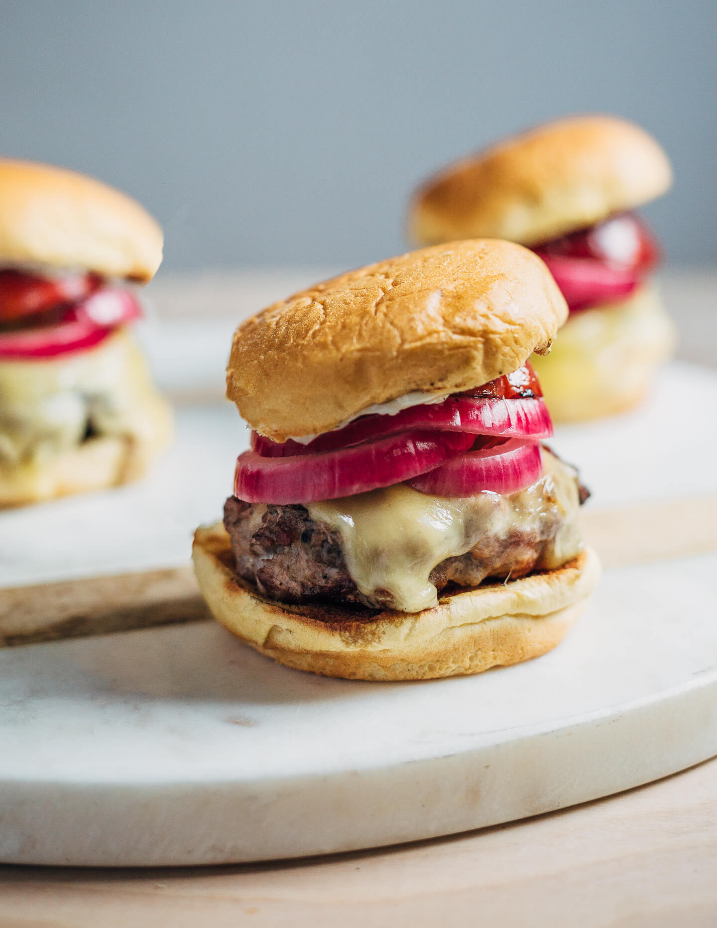 Juicy pork burgers perfectly grilled and topped with velvety melted Raclette cheese, grilled nectarine slices, crisp pickled red onions, and a smear of mayo.